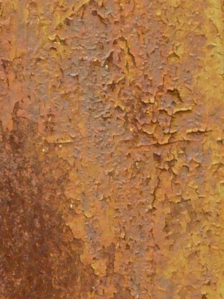 Yellow metal texture, covered with streaks and patches of rust in various shades of pink, red and grey.